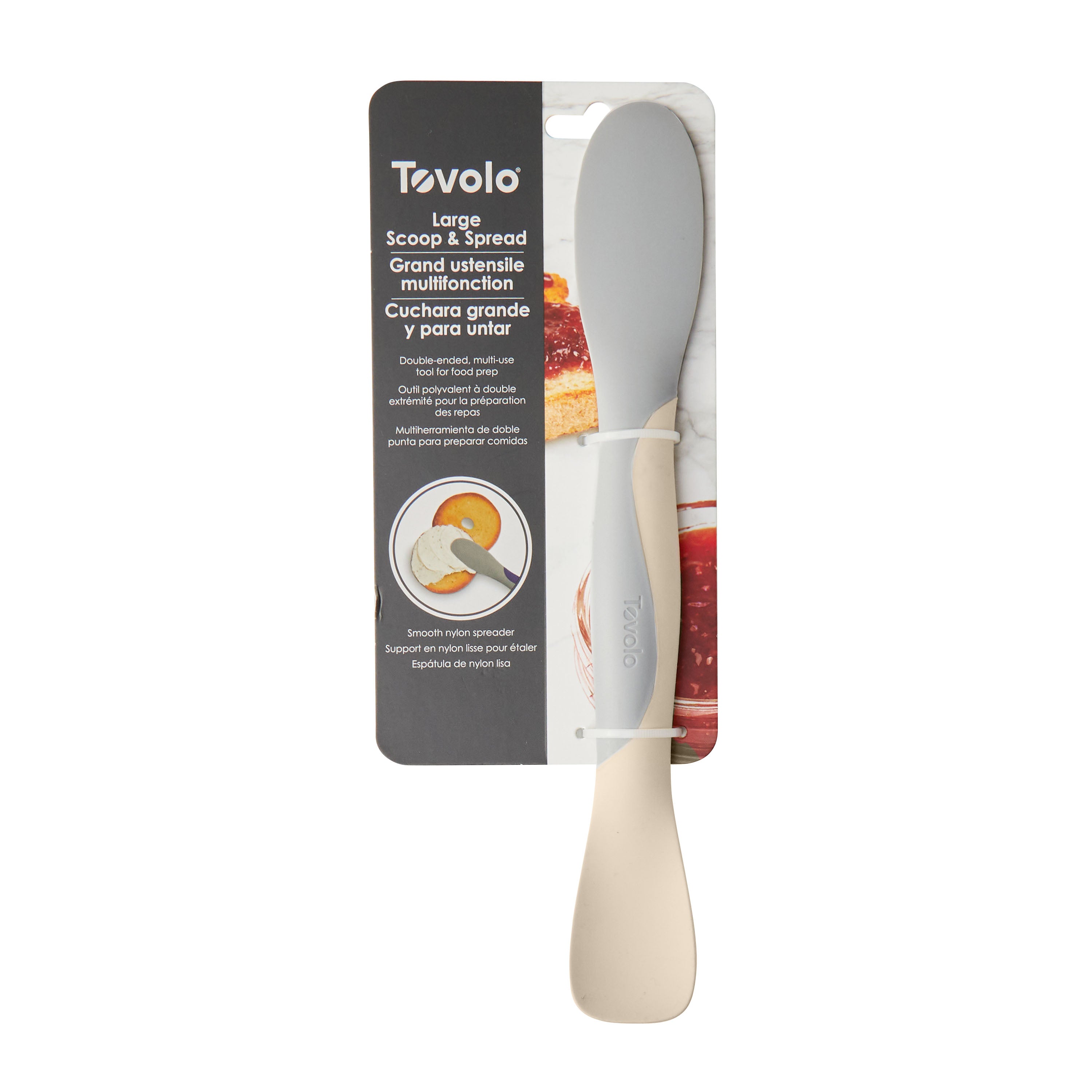A Scoop and Spread kitchen tool in packaging, with a beige handle and gray spreader. Product info is in English, French, and Spanish. The image shows this versatile tool spreading jam on bread.