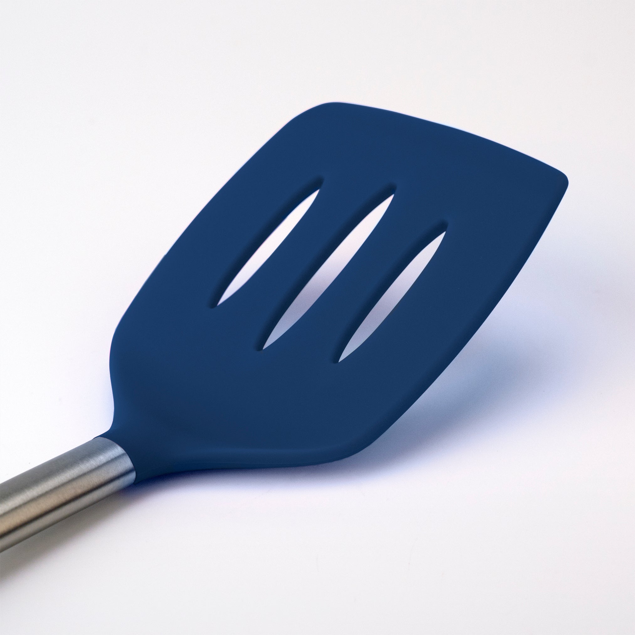 A close-up of the Silicone Slotted Turner, featuring a blue silicone head with slots and a stainless steel handle, nonstick safe and shown against a plain white background.