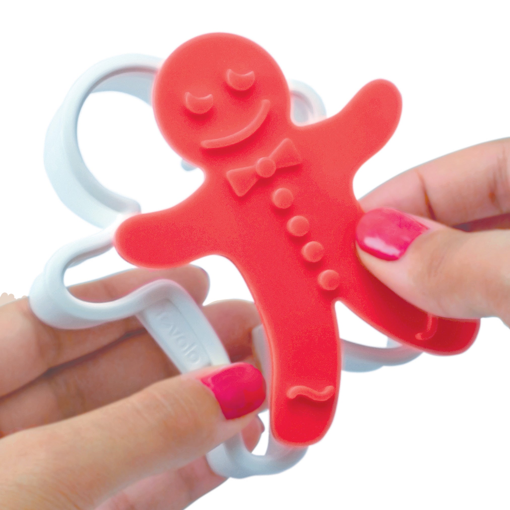A person with pink-painted nails holds a red Gingerbread Cookie Cutter, shaped like a gingerbread man with a smiling face, bow tie, and buttons, all outlined by a white plastic frame—perfect for Christmas cookies.