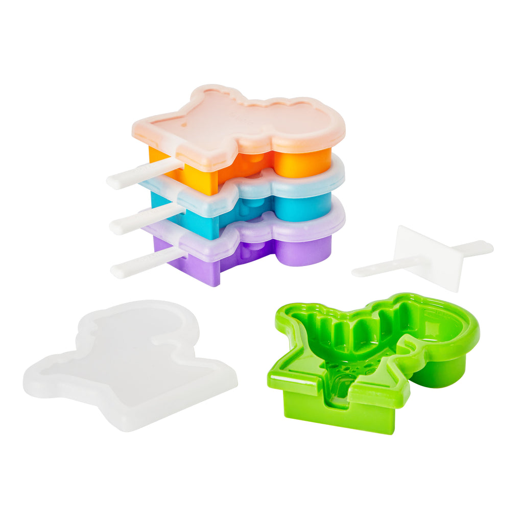 The Pop Molds Stackable set features colorful dinosaur-shaped silicone popsicle molds with white sticks, a green open mold showing its shape, plus a white lid and small spatula—all displayed on a white background.
