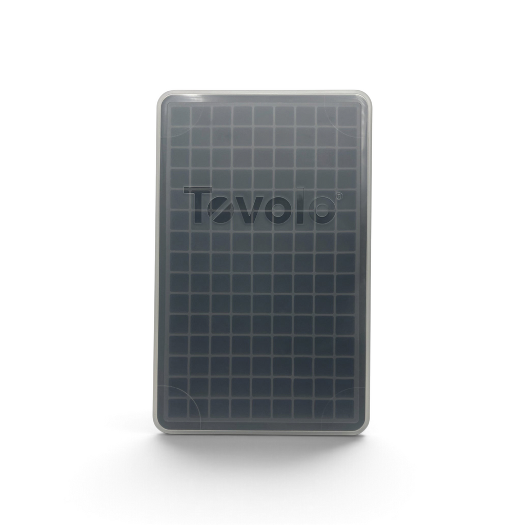 The Mini Ice Mold is a rectangular silicone tray with a clear lid, featuring a 10x6 grid for making small square mini ice cubes that quickly chill drinks. The lid displays the Tovolo brand name.