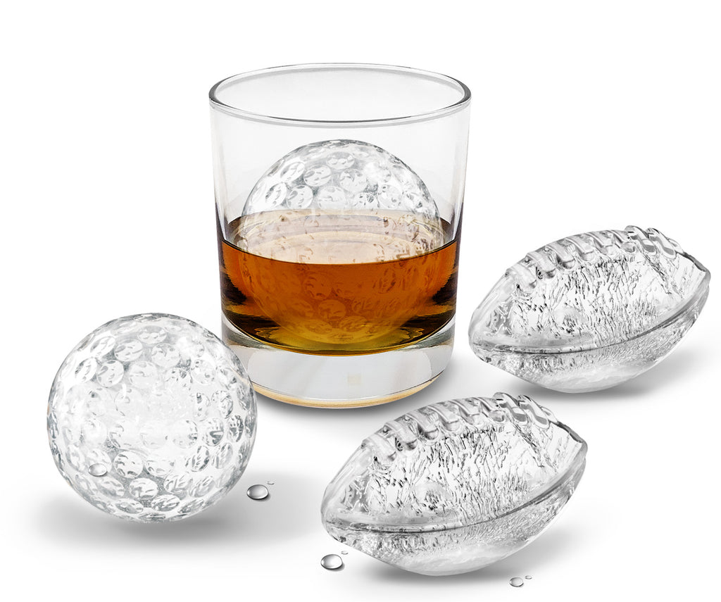 A glass of whiskey with a tovolo Golf and Football Sports Ice Mold (Set of 4) golf ball-shaped ice inside, with two more golf ball ice cubes beside it on a white background.