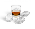 A glass of whiskey with a football-shaped ice cube, made using tovolo’s Golf and Football Ice Molds (Set of 4), sits beside two more matching ice cubes on a white background.
