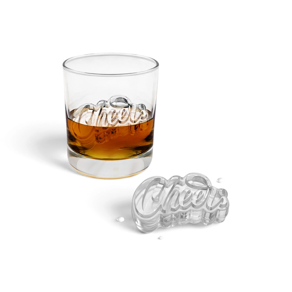 A glass of whiskey with a large Cheers-shaped ice cube made from tovolo's Cheers Ice Molds (Set of 2) inside, and another Cheers-shaped ice cube beside the glass on a white surface.