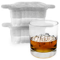 A glass of whiskey labeled "Cheers" sits before two stacked tovolo Cheers Ice Molds (Set of 2), speckled silicone trays with lids crafted to make spherical ice cubes, ideal for fans of craft ice in their drinks.