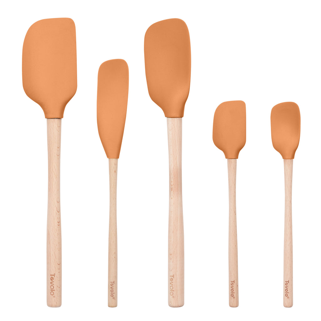 The Flex-Core Wood-Handle Spatula Set of 5 includes classic spatulas and a jar scraper with orange silicone heads and light wood handles, arranged in various sizes and shapes.