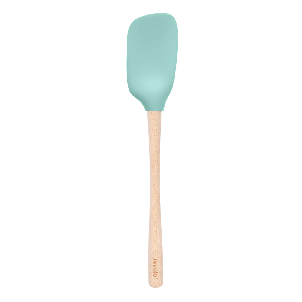 The tovolo Flex-Core Silicone Spoonula features a light blue silicone head and a light wooden handle, shown against a white background.
