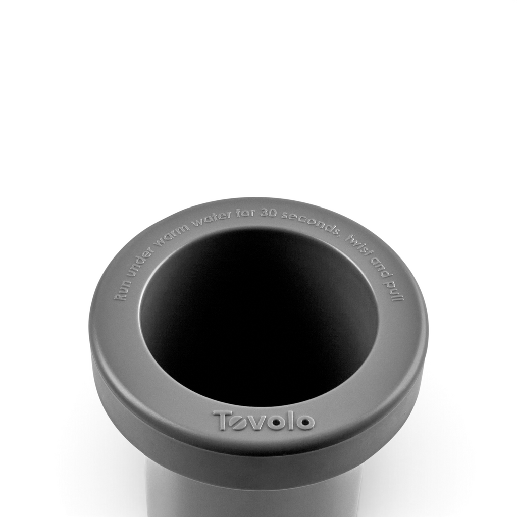 A close-up of a gray Squeeze and Release Mini Ice tool shows its round opening with embossed instructions: "Run under warm water for 30 seconds. Twist and pull," around the rim.
