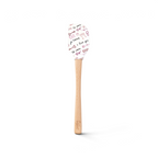The Spring Spatulart features a wood handle and a white silicone head decorated with red and black handwritten "I love you," "te amo," hearts, and XOXO—perfect for adding a touch of love to your baking.