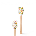 The Spring Spatulart set includes two wood-handled spatulas with silicone heads, featuring a carrot patch design with colorful carrots, tomatoes, cucumbers, and herbs on a white background.