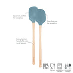 The tovolo Flex-Core Silicone Mini Spatula + Spoonula set includes two blue, heat-resistant utensils with wooden, long handles—one for scooping, one for spreading. Safety icons appear at the bottom.