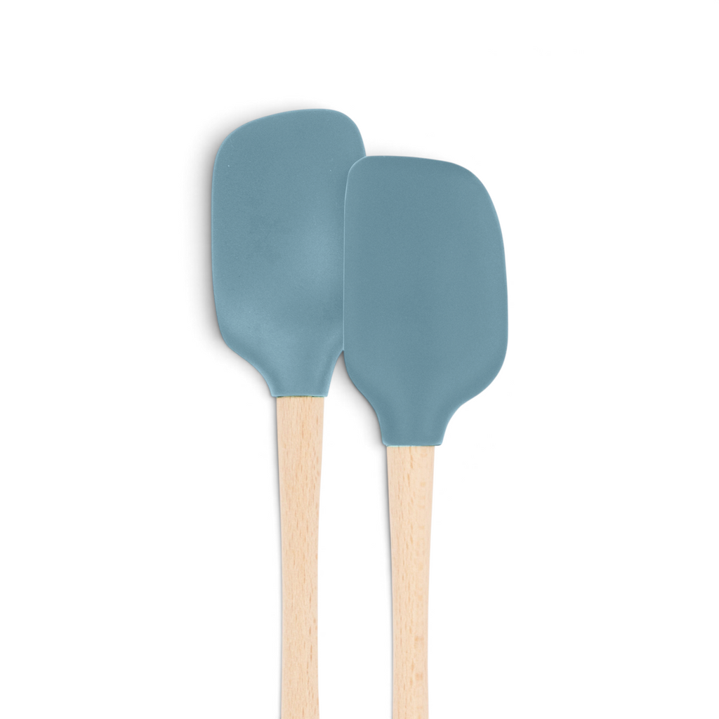 The tovolo Flex-Core Silicone Mini Spatula + Spoonula, both heat-resistant with light wooden handles and blue-gray heads, stand upright side by side against a white background.