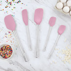 Five Flex-Core All-Silicone Spatula Set of 5 pieces are displayed on a marble countertop with eggs, white chocolate chips, and a bowl of colorful sprinkles—perfect for baking or using as a classic spatula or jar scraper.