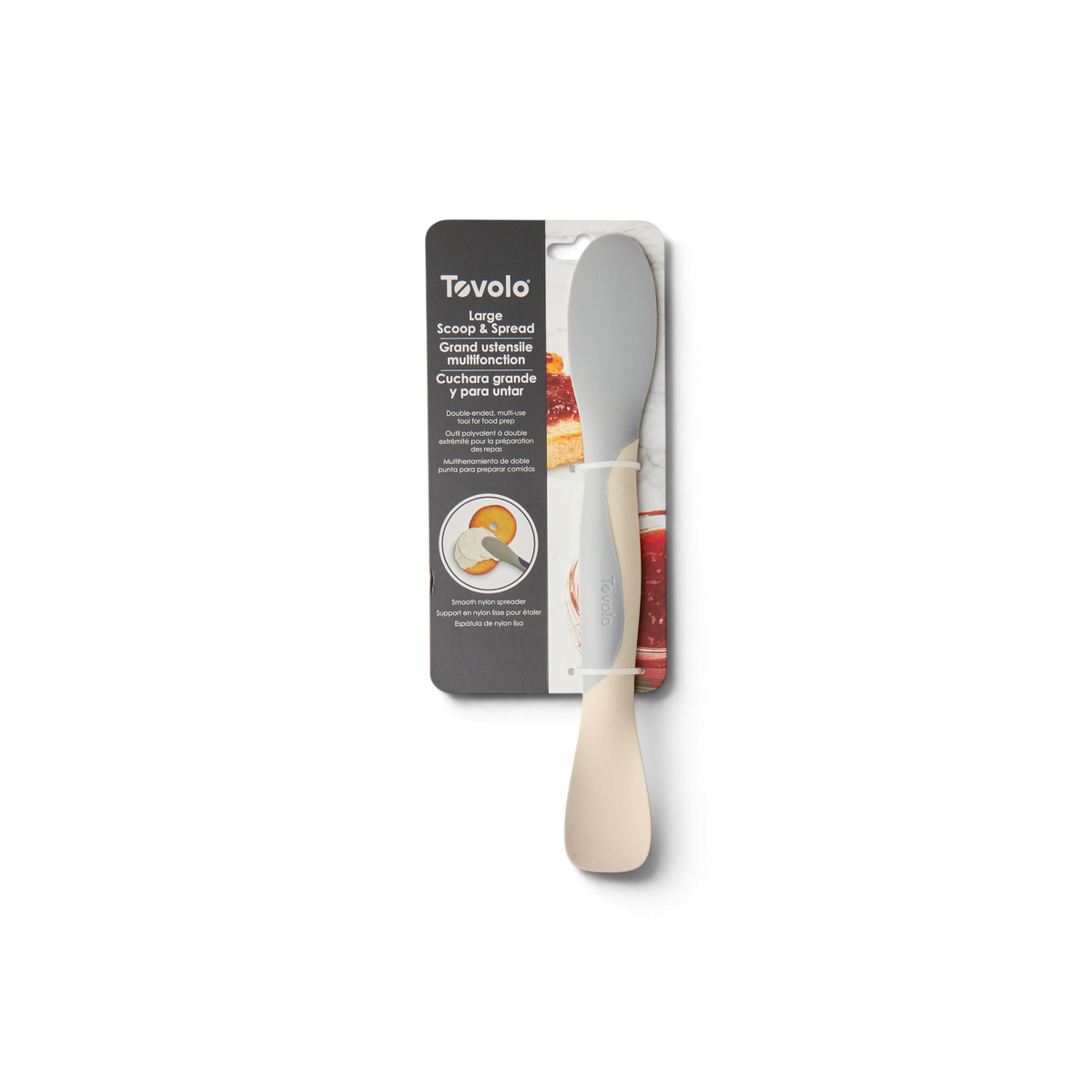 A Scoop and Spread kitchen tool in packaging, with a beige handle and gray spreader. Product info is in English, French, and Spanish. The image shows this versatile tool spreading jam on bread.