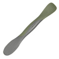 The Scoop and Spread is a double-ended kitchen tool in gray and olive green, shown on a white background. With a broad, flat end for scooping and spreading and a narrower opposite end, it’s the perfect helper for bakers.