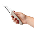 A hand with red-painted nails holds the Precision Straight Peeler, featuring a stainless steel blade, against a white background.