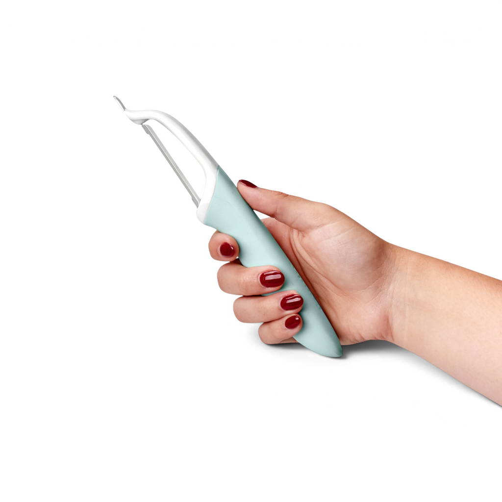A hand with red nail polish holds the Precision Straight Peeler, featuring a light blue and white stainless steel design, against a plain white background.