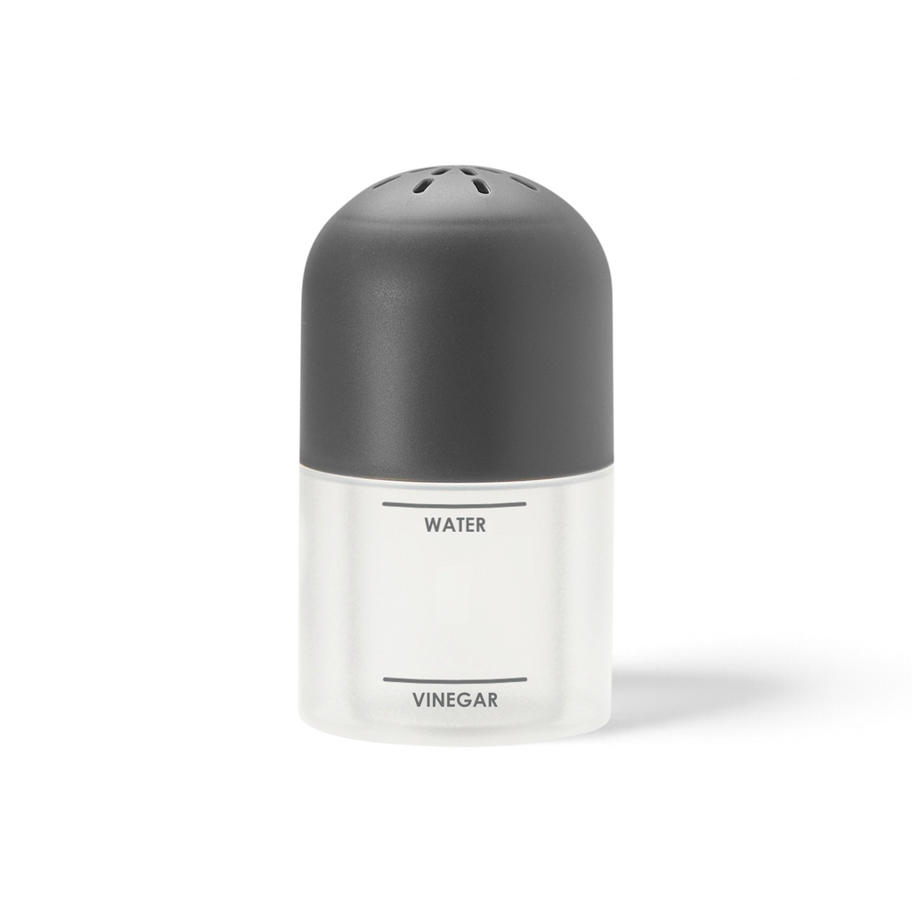 The Microwave Steam Cleaner, a clear container with a black lid labeled "WATER" on top and "VINEGAR" below, is designed for easy microwave cleaning and stands upright against a white background.