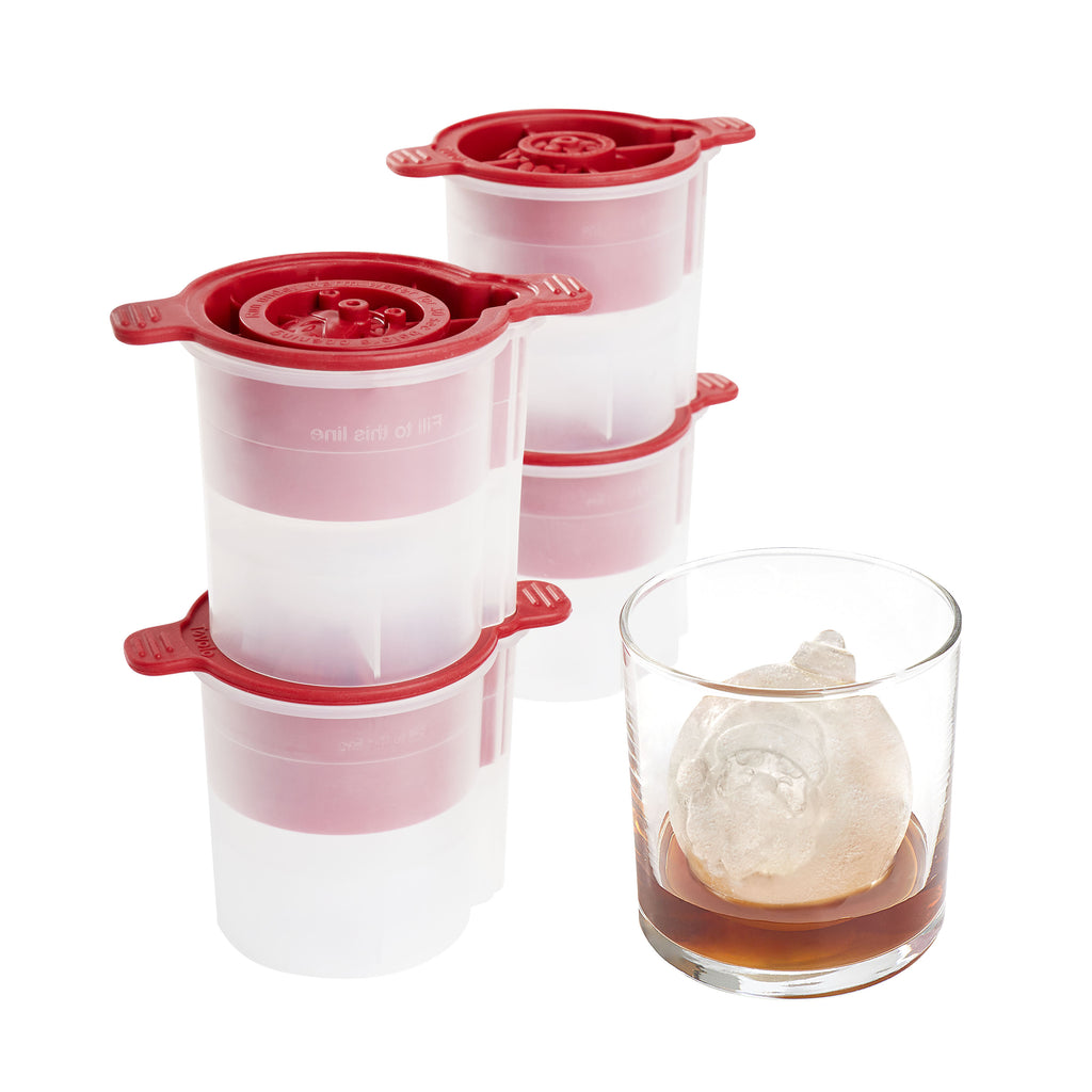 The tovolo Christmas Ornament Ice Molds (Set of 4) with festive red lids are shown beside a glass of whiskey, each making round holiday-themed ice—sleek and perfect as a Christmas gift for cocktail enthusiasts.