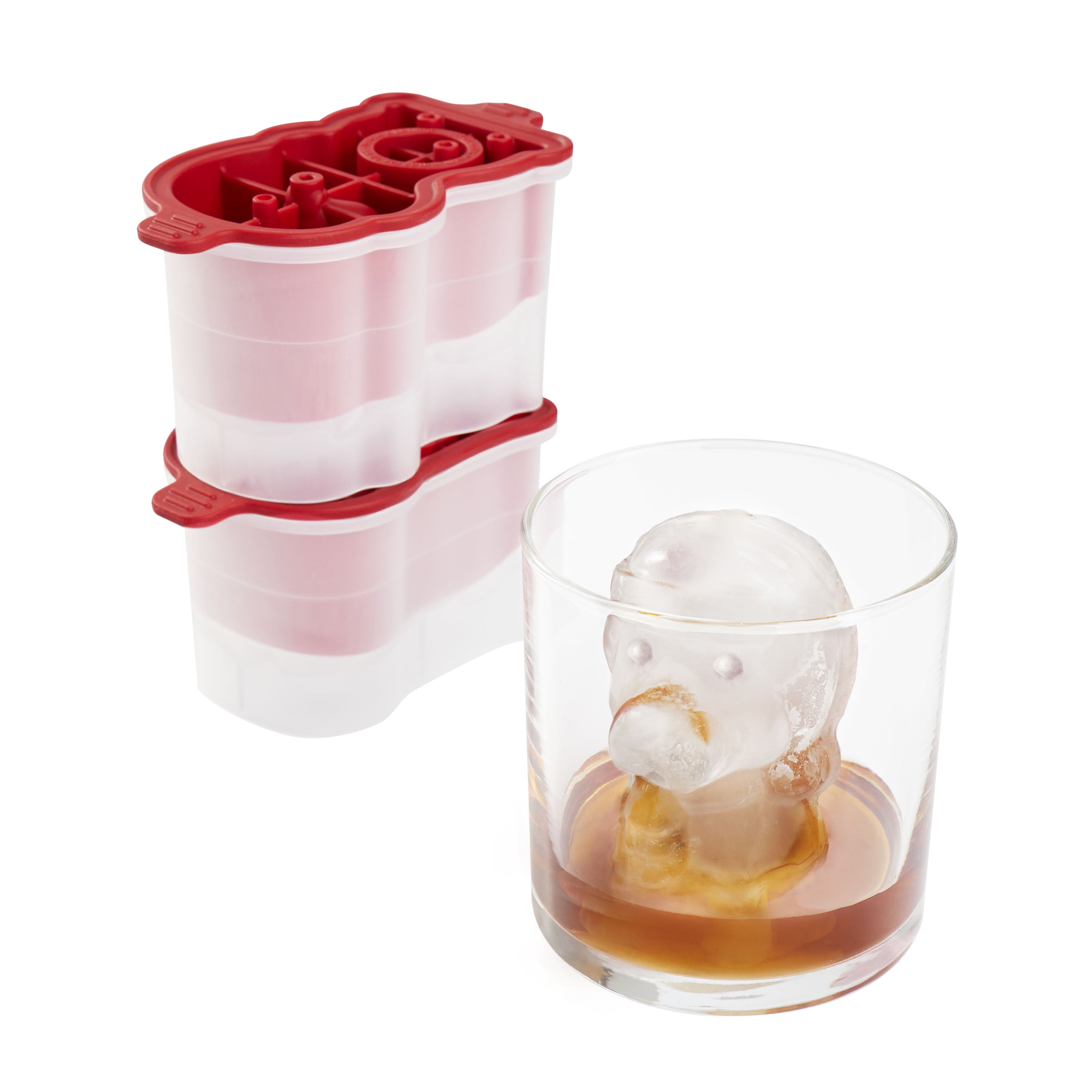 A glass of brown liquor with a large cartoon-shaped ice cube sits beside the tovolo Santa Paws Ice Mold (Set of 2), a festive red and white mold ideal for adding holiday cheer or gifting at Christmas.