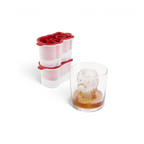 A glass of brown liquor with a large cartoon-shaped ice cube sits beside the tovolo Santa Paws Ice Mold (Set of 2), a festive red and white mold ideal for adding holiday cheer or gifting at Christmas.
