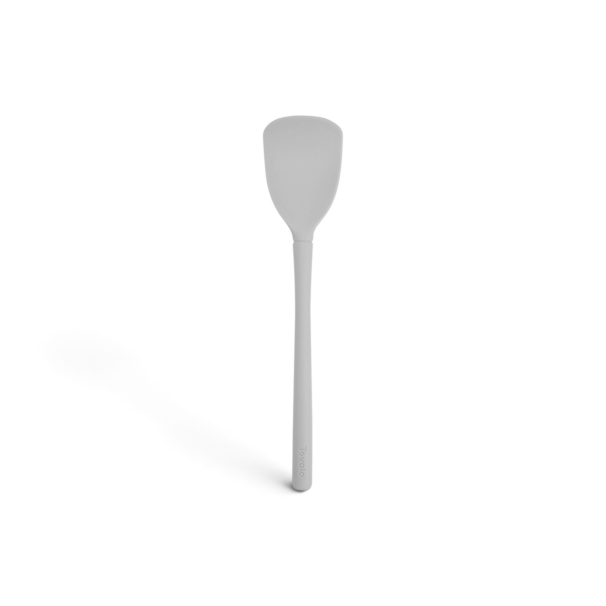 The Flex-Core Scoopula, featuring a long handle and flat, rounded head in gray silicone, stands vertically on a white background.