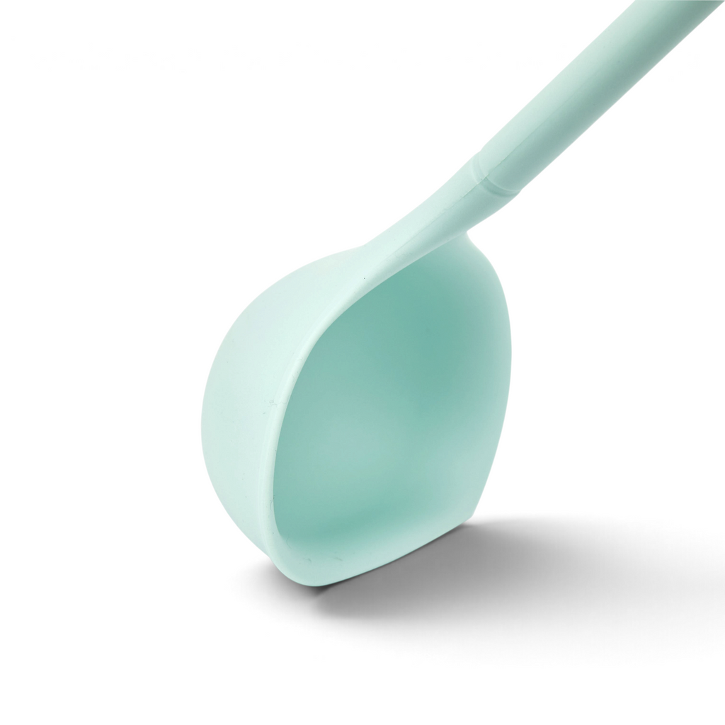 The tovolo Flex-Core Silicone Ladle in light blue features a wide, rounded scoop and angled edge, shown against a white background.