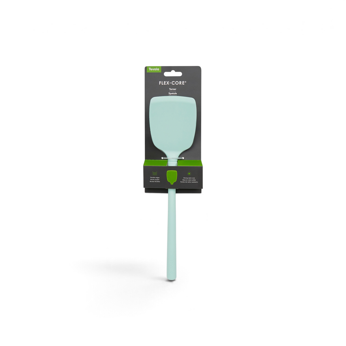 A tovolo Flex-Core Silicone Solid Turner in light green is shown in its packaging, which features a wide flexible head, long handle, and black packaging with green accents and white text.