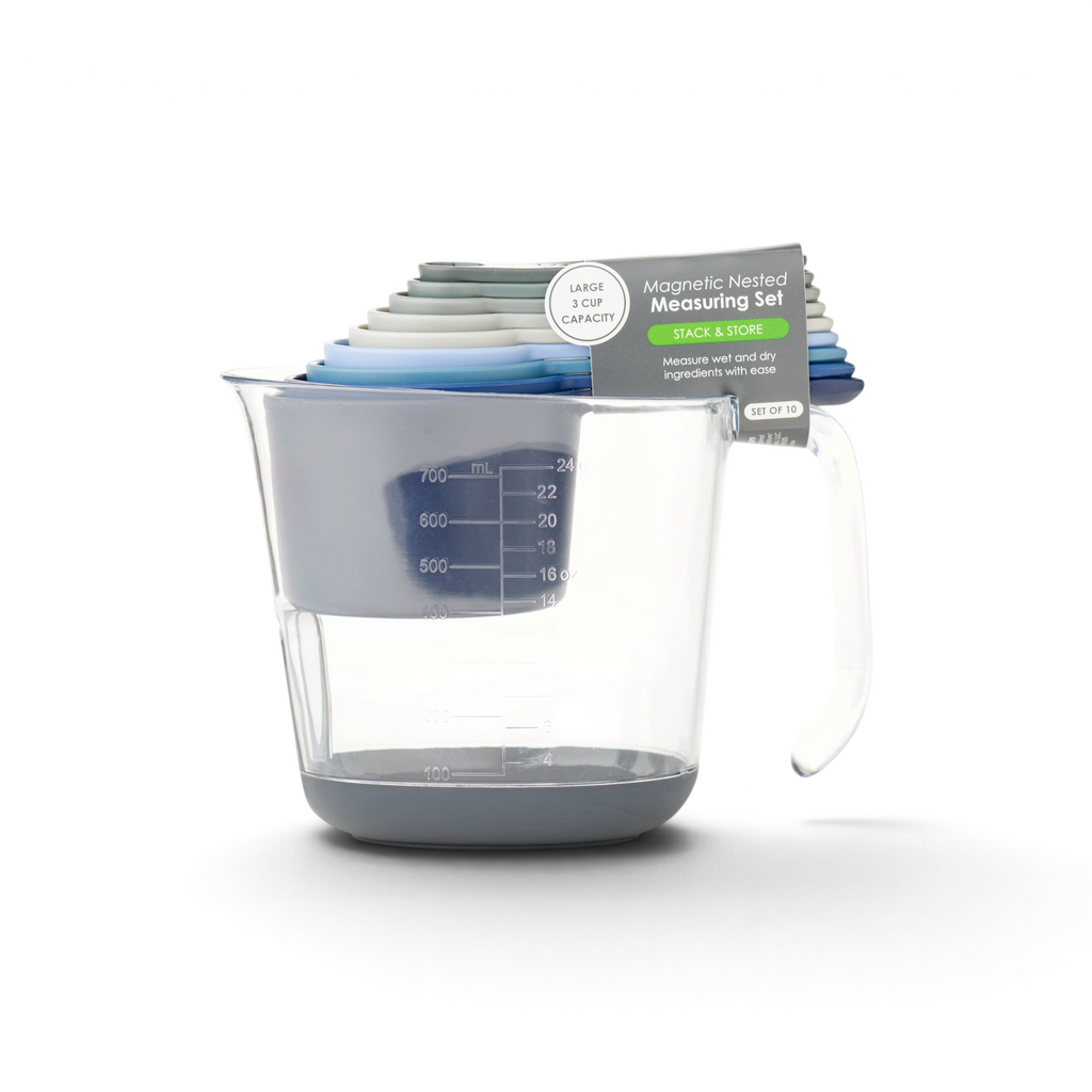 A clear measuring cup with a handle holds a colorful, stackable Magnetic Nested Measuring System. The cups are magnetic for easy stacking and storage, and the set is clearly labeled.