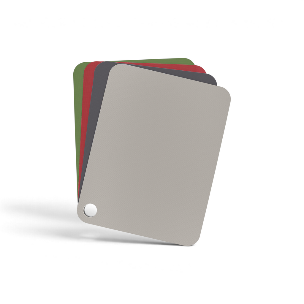 Four Flexible Cutting Mats in gray, red, dark gray, and green, fanned out with a hole in the bottom left corner, resemble color sample swatches and are shown on a white background.