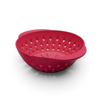 The Mini Berry Colander is a red plastic colander with round holes and two handles, ideal for washing fruit or draining pasta and vegetables. Shown on a white background.