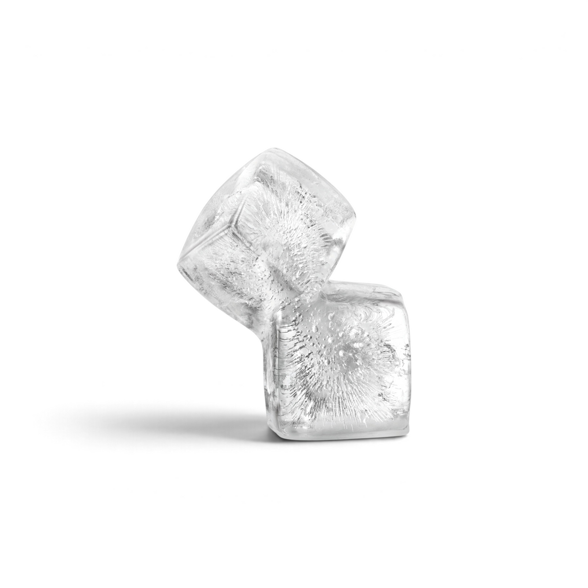 Two clear ice cubes made with tovolo Double Rocks Ice Molds (Set of 2) are stacked at an angle on a white background, highlighting visible air bubbles and unique textures inside the ice.