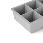 Close-up of a gray tovolo King Cube Silicone Ice Mold with four large square compartments, ideal for making craft ice, and featuring the brand name embossed on the side.