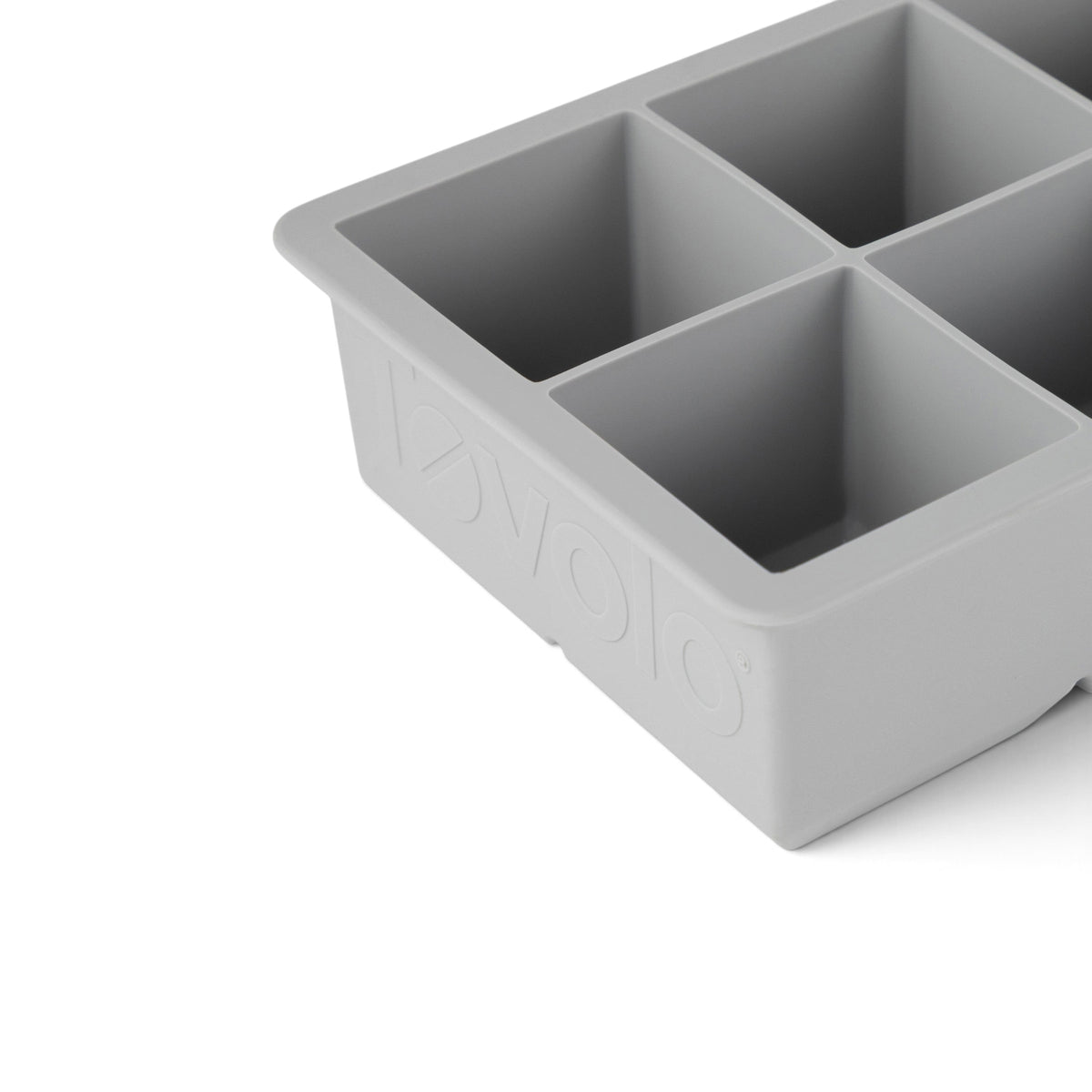 Close-up of a gray tovolo King Cube Silicone Ice Mold with four large square compartments, ideal for making craft ice, and featuring the brand name embossed on the side.