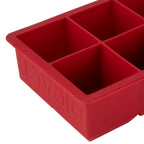 Close-up of a red King Cube Silicone Ice Mold by tovolo with four large square compartments for extra-large ice cubes and the brand name embossed on the side.