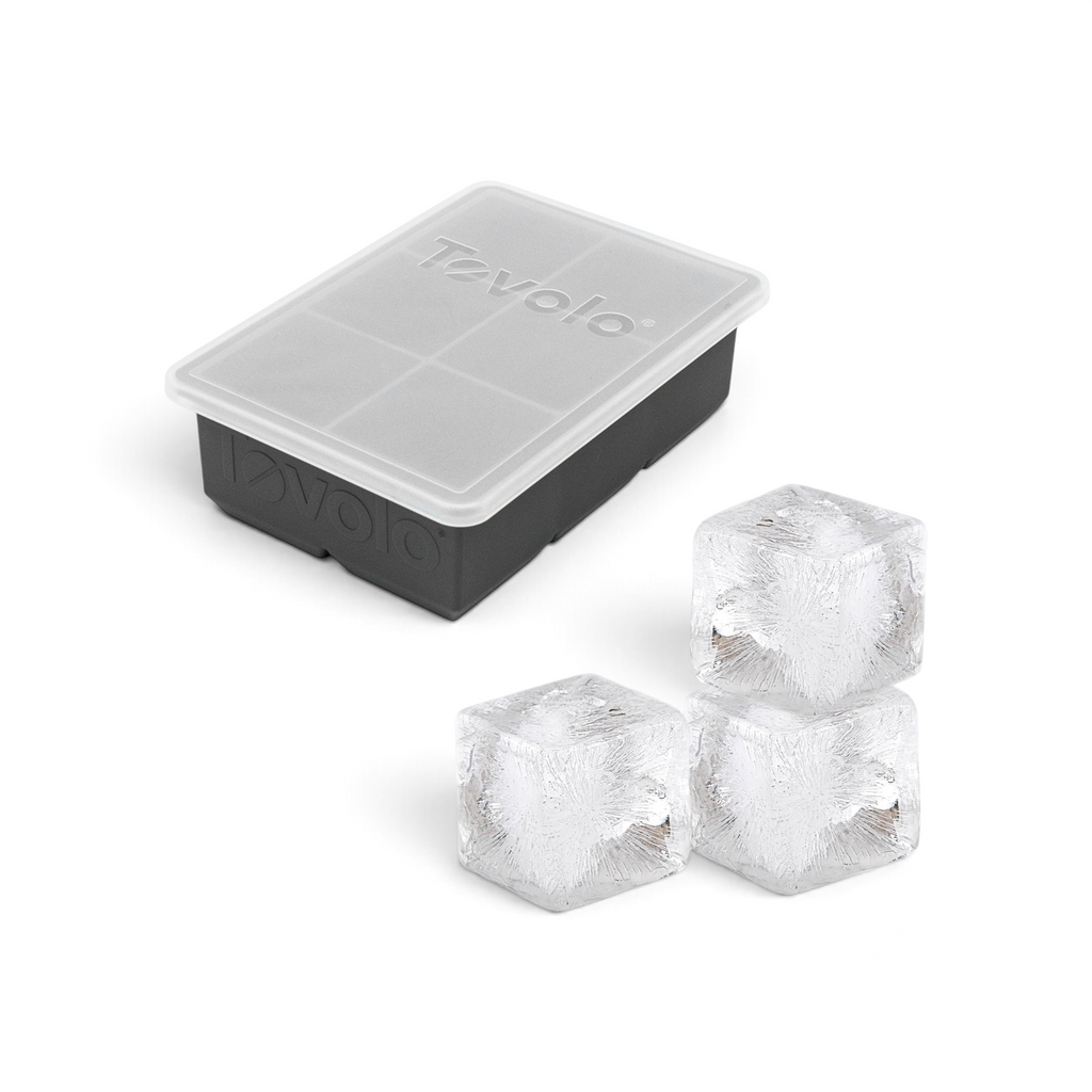 The tovolo King Cube Silicone Ice Mold in black features a translucent lid and is shown with three large, clear ice cubes placed in front.