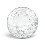 A clear, round ice sphere shaped like a baseball, made with tovolo Baseball Ice Molds (Set of 2), rests on a white surface with a subtle shadow underneath.