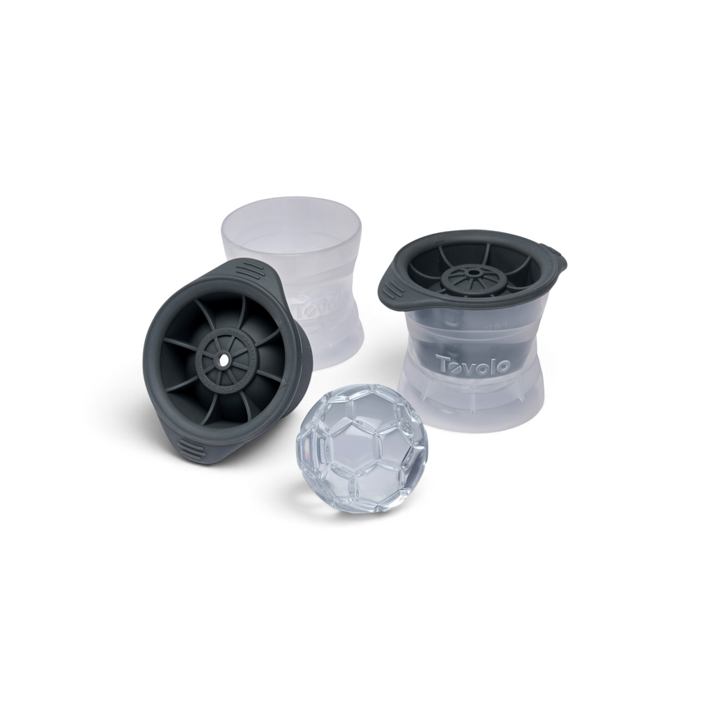 Two spherical, stackable Baseball Ice Molds by tovolo are shown with black lids and translucent bases, one open to reveal a clear, baseball-shaped ice cube. The brand name "tovolo" is visible on the side of these craft ice molds.