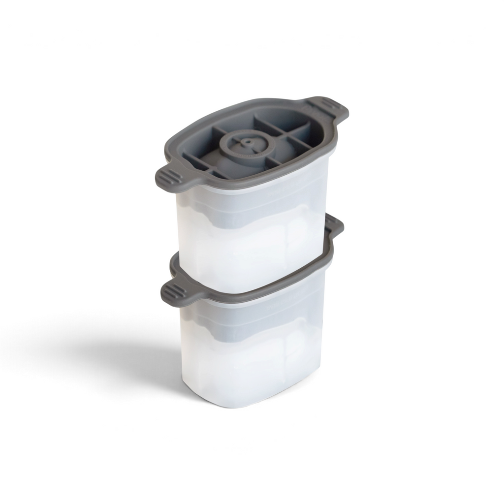 The tovolo Dog Ice Molds (Set of 2) feature stackable, clear rectangular containers with gray lids and side handles. Each silicone mold has four compartments with central circular openings for easy, organized ice storage.