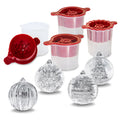 The tovolo Holiday Ice Molds set includes four clear molds with red lids and a white measuring cup, creating festive snowflake, Christmas tree, striped, and ridged ice balls—perfect for holiday cocktails or as a unique Christmas gift.