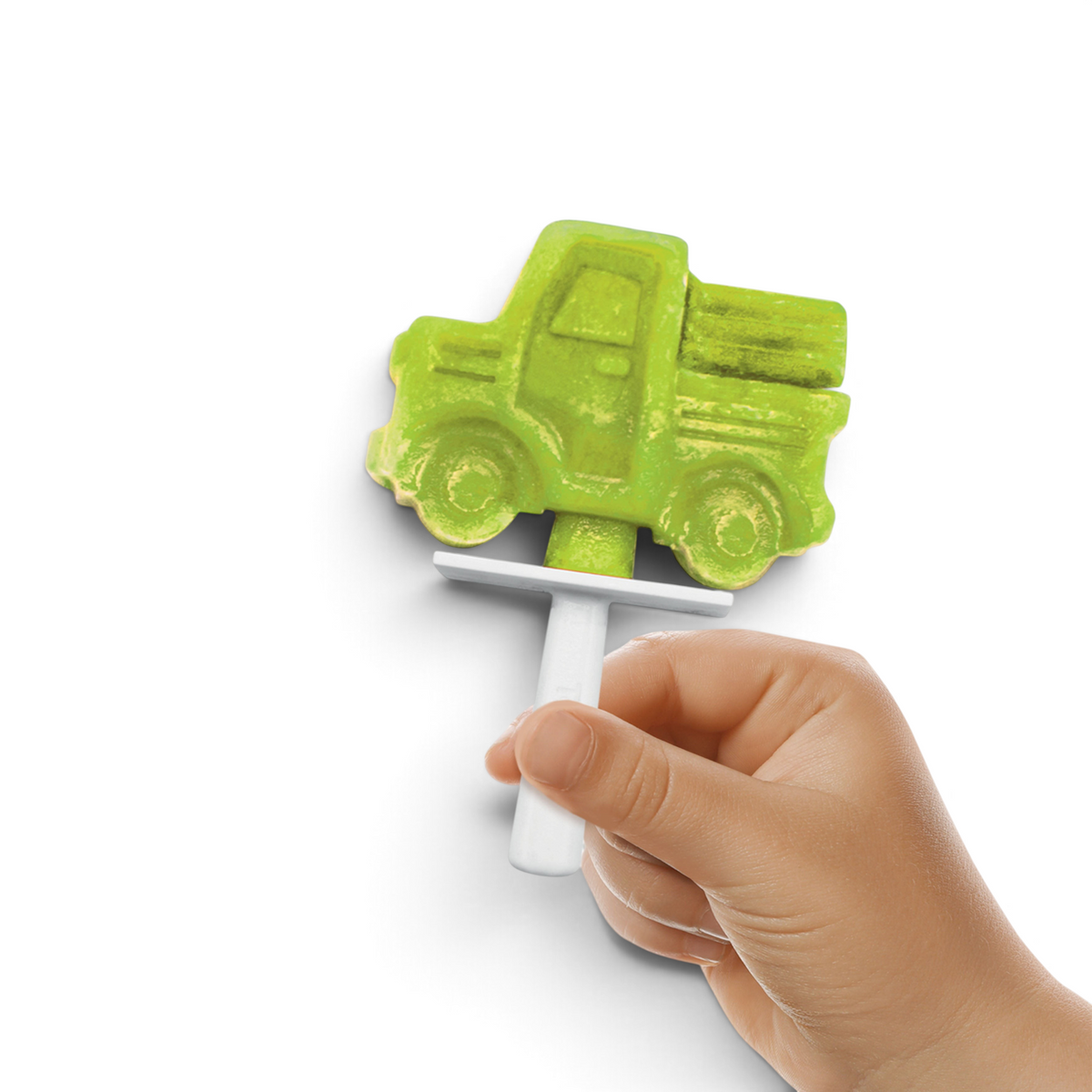 A hand holds a green popsicle shaped like a pickup truck, made with Stackable Pop Molds and a white plastic stick, against a plain white background.