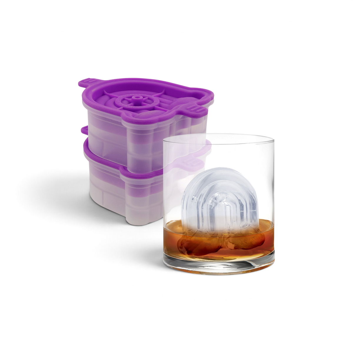 A clear glass of whiskey with a rainbow-shaped ice cube inside sits beside two tovolo Rainbow Ice Molds (Set of 2) in vibrant purple silicone.