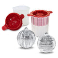 The tovolo Santa and Reindeer Ornament Ice Molds (Set of 2) in red and white plastic make a perfect Christmas gift, with two clear spherical ice balls in front and a small translucent measuring cup beside the molds.
