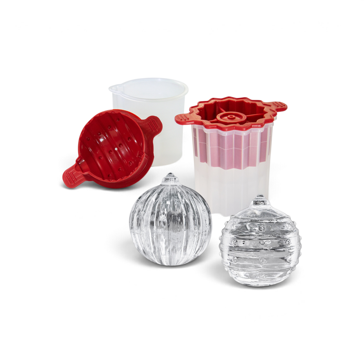 The tovolo Santa and Reindeer Ornament Ice Molds (Set of 2) in red and white plastic make a perfect Christmas gift, with two clear spherical ice balls in front and a small translucent measuring cup beside the molds.