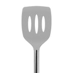 The Silicone Slotted Turner features a gray silicone head with three oval slots, a stainless steel handle, and is safe for nonstick cookware. Shown against a white background.