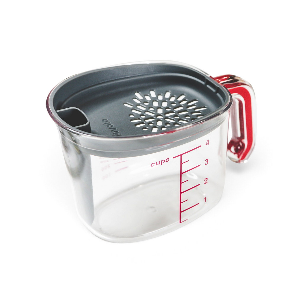 The Gravy Strainer is a clear plastic measuring cup with red markings and a gray silicone lid that features a strainer and pour spout, displayed on a white background.