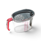 The Gravy Strainer is a clear plastic measuring cup with a red handle, gray silicone strainer lid, red markings up to 1000 mL. The cup is empty and shown isolated on a white background.