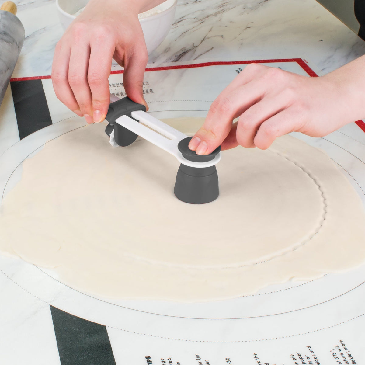 Using the Precision Pie Crust Cutter, a person cuts even circles from dough on a floured surface.