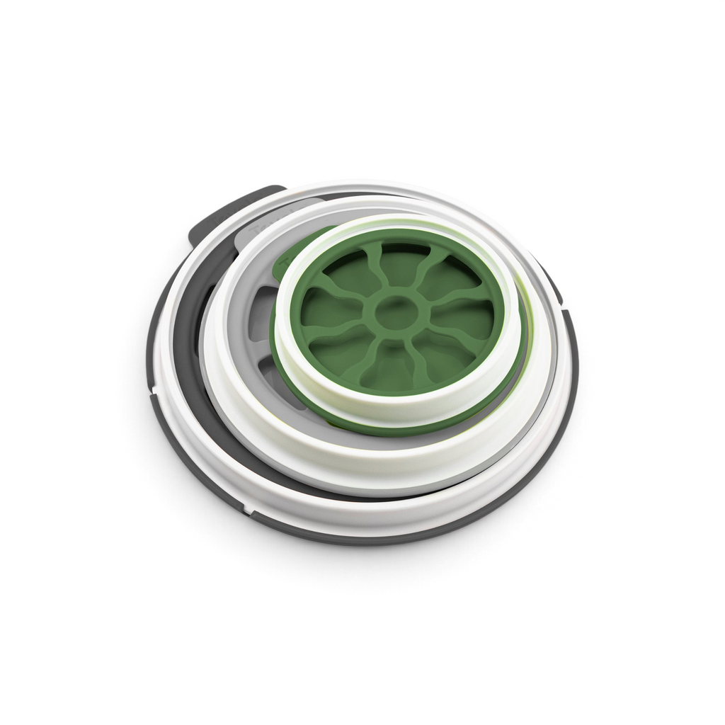 A close-up of Seal & Store, a round green and white airtight container with a wheel-like center and gray and white circular rims—perfect for keeping produce fresh.