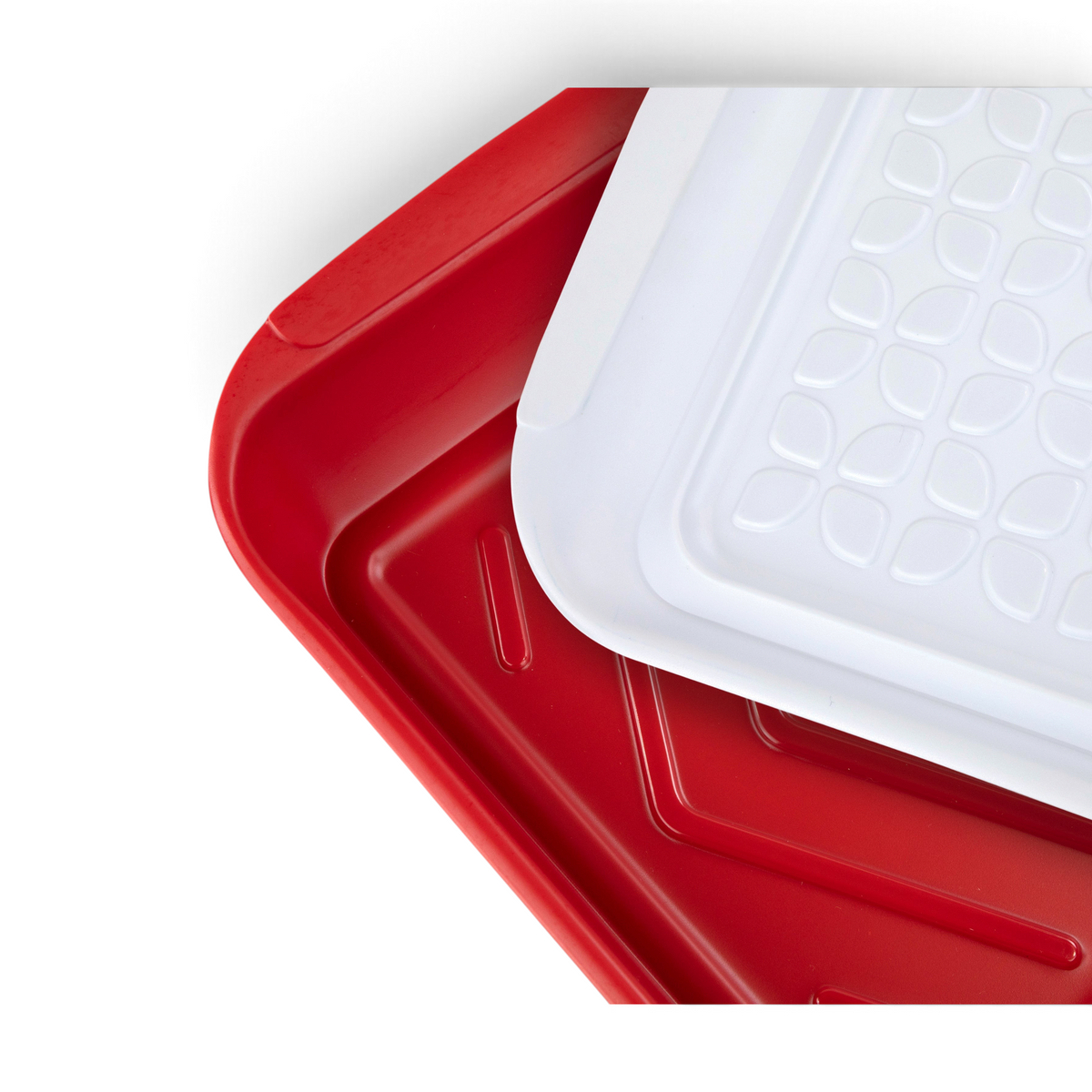 Two Marinade Trays—one solid red, the other white with a geometric pattern—are stacked at an angle. The red tray is on the bottom, partially covered by the patterned white tray, showcasing a versatile kitchen grilling accessory.